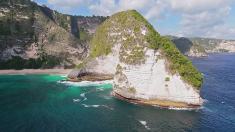 4K Drone shot of ocean wave washing over Kelingking Beach in Nusa Penida Video Stock Footage 276236433