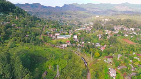 4K Drone shot of Train Approaching Rural Town Across Verdant Mountain Landscape Stock Footage 321551509