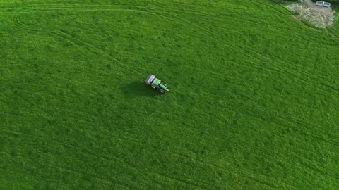4K drone top-down tractor spreading fertiliser across green pasture field Stock Footage 334103245