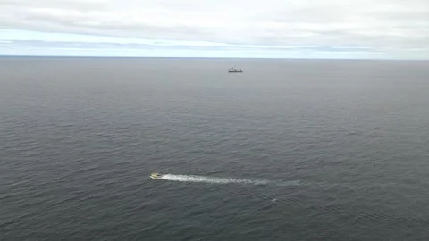 4K Drone Tracking Shot of Small Boat Crossing North Sea with Survey Ship Stock Footage 340414445