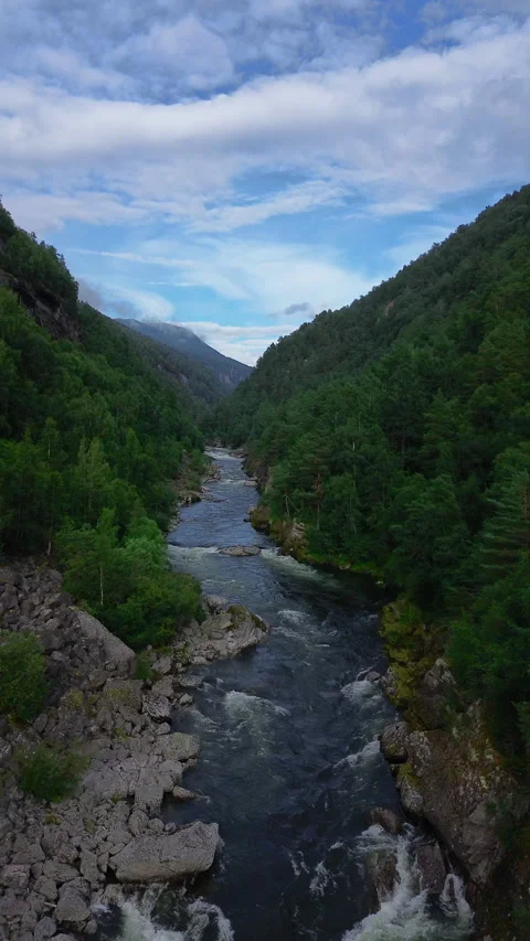 4K drone view of a serene river flowing through lush green mountains in Norway Stock Footage 296026133