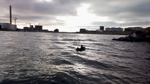 4K, ducks swimming at dusk, backlit, rocky shore. buildings in background Stockbeeldmateriaal 147187610
