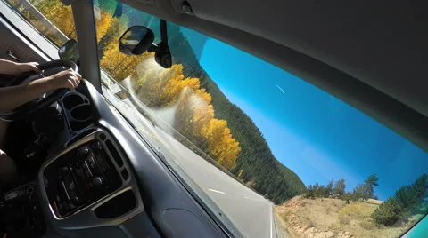 4K Dutch angle hands on wheel driving mountain road on fall day golden aspens Stock Footage 55458544