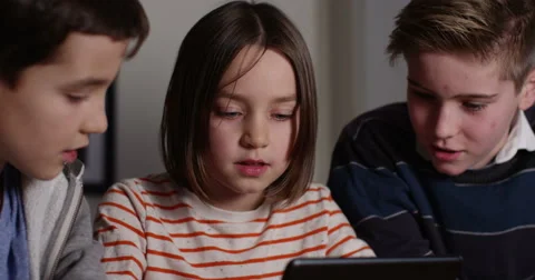 4k, Elder brothers watch their little sister play games on a digital tablet. Slo Stock Footage 61373105
