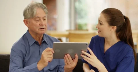 4K Elderly man learning how to use computer with help from home support nurse Video stock 81191675