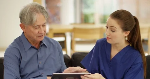 4K Elderly man learning how to use computer with help from home support carer Stock Footage 81474732