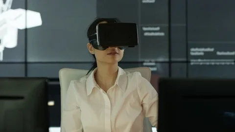 4K Engineer wearing VR viewer at desk with animated graphic in background Stock Footage 75963225