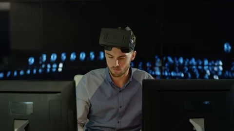 4K Engineer wearing VR viewer at desk with animated graphic in background Stock Footage 75968744