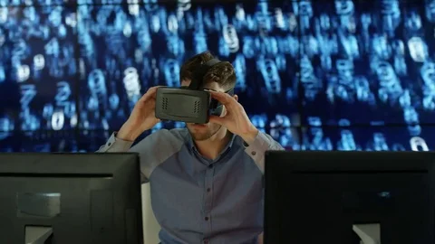 4K Engineer wearing VR viewer at desk with animated graphic in background Video stock 75969063