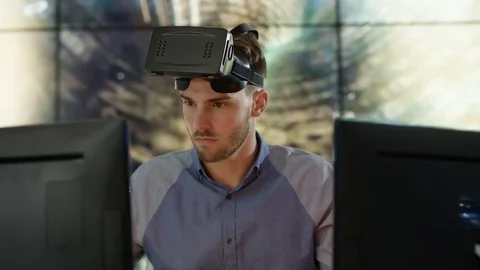 4K Engineer wearing VR viewer at desk with animated graphic in background Video stock 75969225