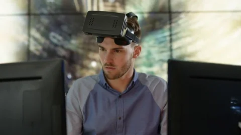 4K Engineer wearing VR viewer at desk with animated graphic in background Video stock 75969476