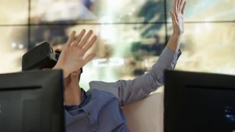 4K Engineer wearing VR viewer at desk with animated graphic in background Video stock 75969966