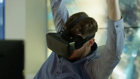 4K Engineer wearing VR viewer at desk with animated graphic in background Video stock 75970380