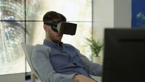 4K Engineer wearing VR viewer at desk with animated graphic in background Video stock 75970469