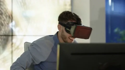 4K Engineer wearing VR viewer at desk with animated graphic in background Stock Footage 75970667