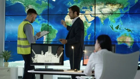 4K Engineering team in discussion looking at world map graphic on video wall Stock Footage 75936553