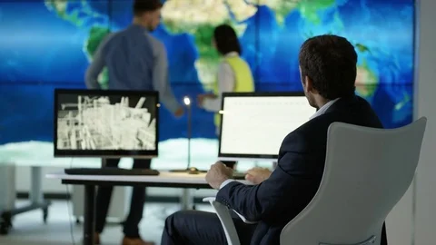 4K Engineering team in discussion looking at world map graphic on video wall Stock Footage 75938975
