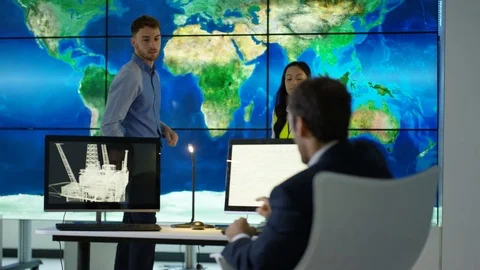 4K Engineering team in discussion looking at world map graphic on video wall Stock Footage 75939018