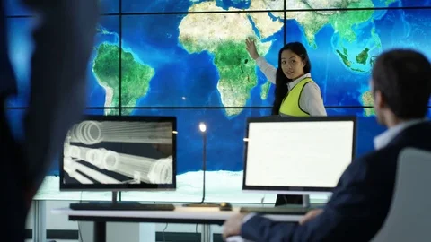 4K Engineering team in discussion looking at world map graphic on video wall Stock Footage 75941170