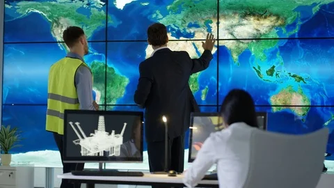 4K Engineering team in discussion looking at world map graphic on video wall Stock Footage 75943588