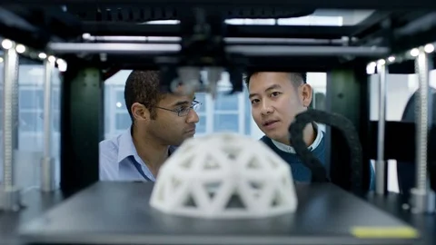 4K Engineers looking at prototype in a 3D printer &amp; checking design on computer. Stock Footage 73867912