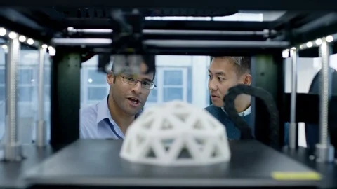 4K Engineers looking at prototype in a 3D printer &amp; checking design on computer. Stock Footage 73867931