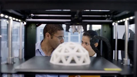 4K Engineers looking at prototype in a 3D printer &amp; checking design on computer. Stock Footage 73869593