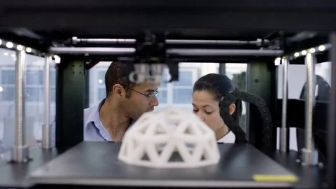 4K Engineers looking at prototype in a 3D printer &amp; checking design on computer. Stock Footage 73869797