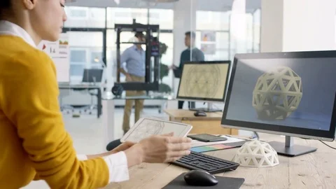 4K Engineers looking at prototype in a 3D printer &amp; checking design on computer. Stock Footage 73871152