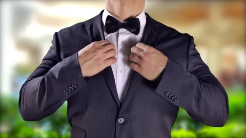 4K Exotic Tropical Locale, Man in Black Suit Bow Tie, Fixing Suit and Tie Stock Footage 71745510