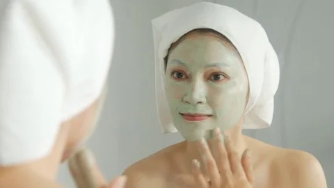 4k of face of smiling woman in mask of cream in bathroom Stock Footage