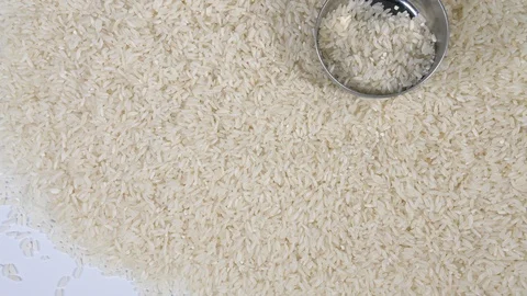 4K falling metal cup on pile of dry white long grain rice from above for cooking Stock Footage 88482350