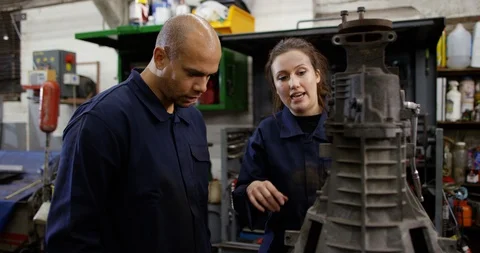 4K Female apprentice mechanic discussing engine repair with experienced coworker Video stock 103054736