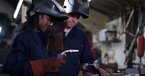 4K Female apprentice welding in workshop with experienced colleague watching Video stock 111631594