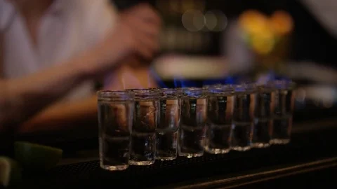4K Female Bartender Setting Light To Row Of Shot Glasses Video stock 75631226