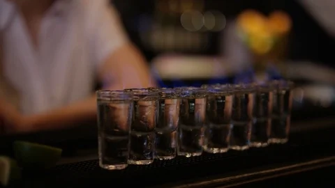 4K Female Bartender Setting Light To Row Of Shot Glasses Video stock 75631325