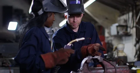 4K Female engineering apprentice working with a mentor in metal workshop Video stock 111631295