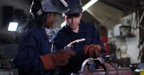 4K Female engineering apprentice working with a mentor in metal workshop Video stock 113098677
