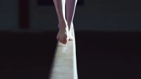 4K Female gymnast training on balance beam in dark gym Stock Footage