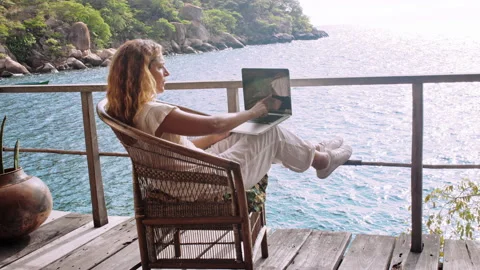4k of Female working on laptop computer, touch screen technology on balcony of b Stockbeeldmateriaal 199626863