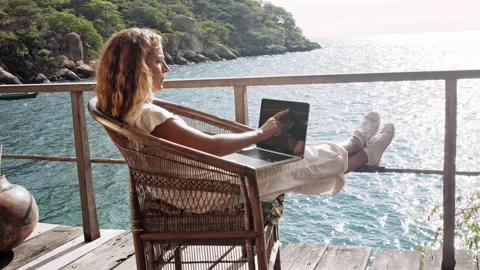 4k of Female working on laptop computer, touch screen technology on balcony of b Stockbeeldmateriaal 199626871