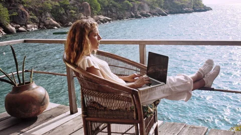 4k of Female working on laptop computer on balcony of bungalow. Successful blogg Stock Footage 199626885