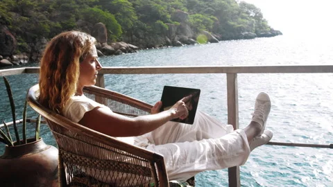 4k of Female working on touch screen tablet computer on balcony of bungalow. Suc Видео 199626838