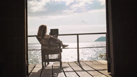 4k of Female working on touch screen tablet computer on balcony of bungalow. Suc Stock Footage 199627036