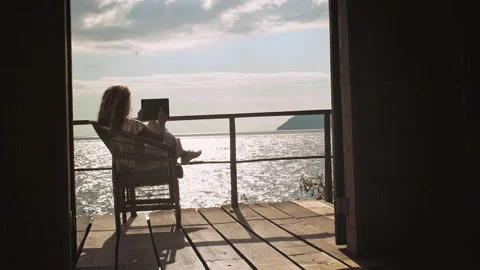 4k of Female working on touch screen tablet computer on balcony of bungalow. Stock Footage 199627055