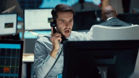 4K Financial trader in busy trading room negotiating a difficult deal over phone Stock Footage