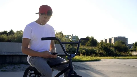 4K Fit man using mobile phoneon BMX bike sending messages on social networks Stock Footage 117725667