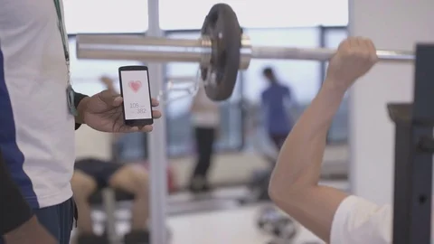 4K Fitness Trainer Using Smartphone App To Train With A Client At The Gym Video stock 75868898