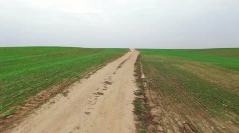4K. Flight and takeoff above green fields with dirt road, aerial  view. Video stock 55573536
