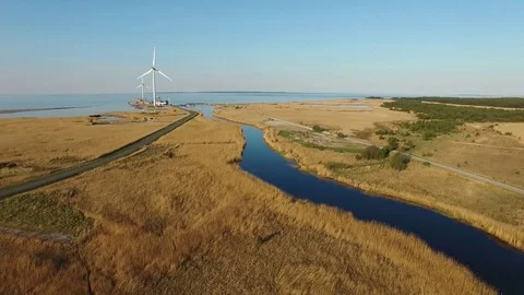 4K. Flight over blue river and fields towards wind turbines near the sea. Stock Footage 72182471